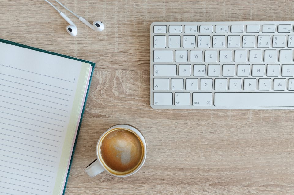 自宅のデスクにノートとキーボード、コーヒーが置かれている